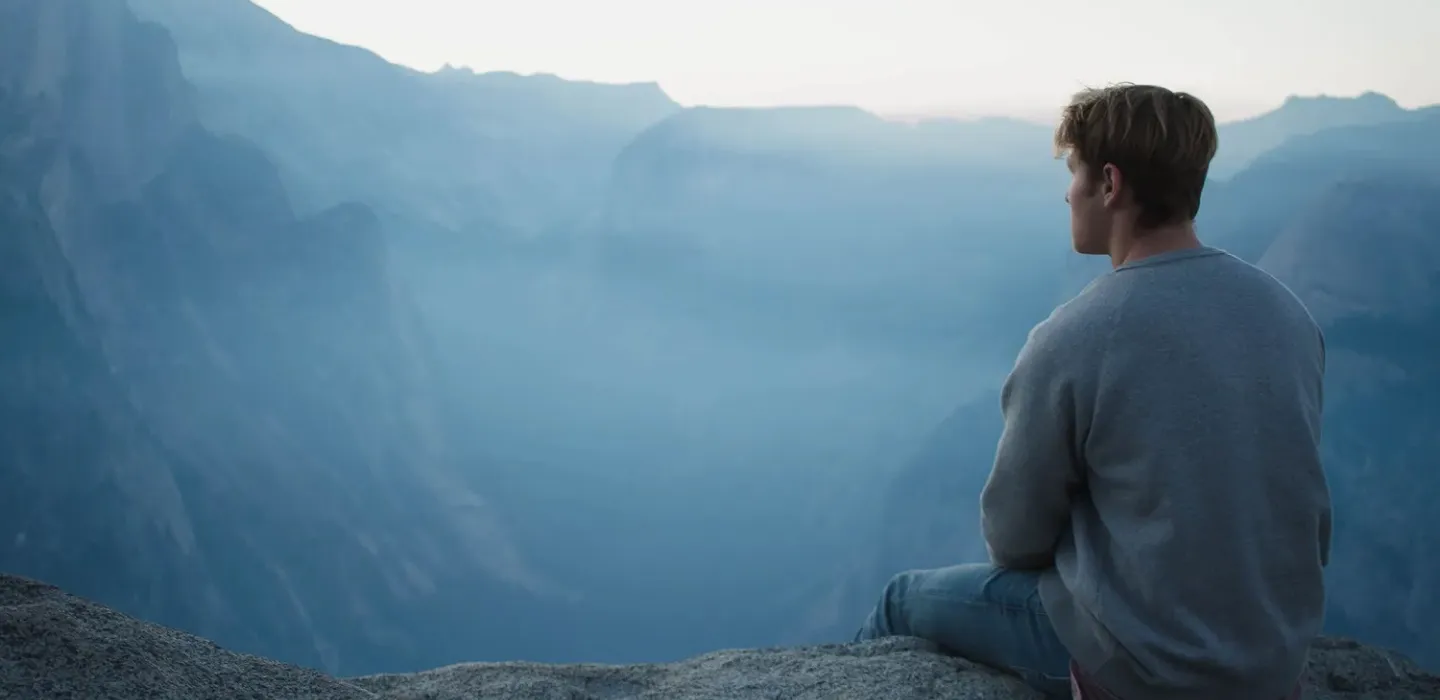 Man Sitting on Cliff Overlooking Horizon